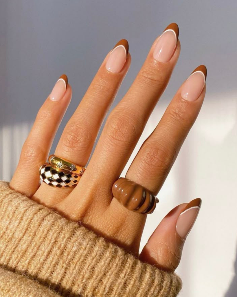 Short almond nails with caramel French tips and a thin white double line. Short nail designs