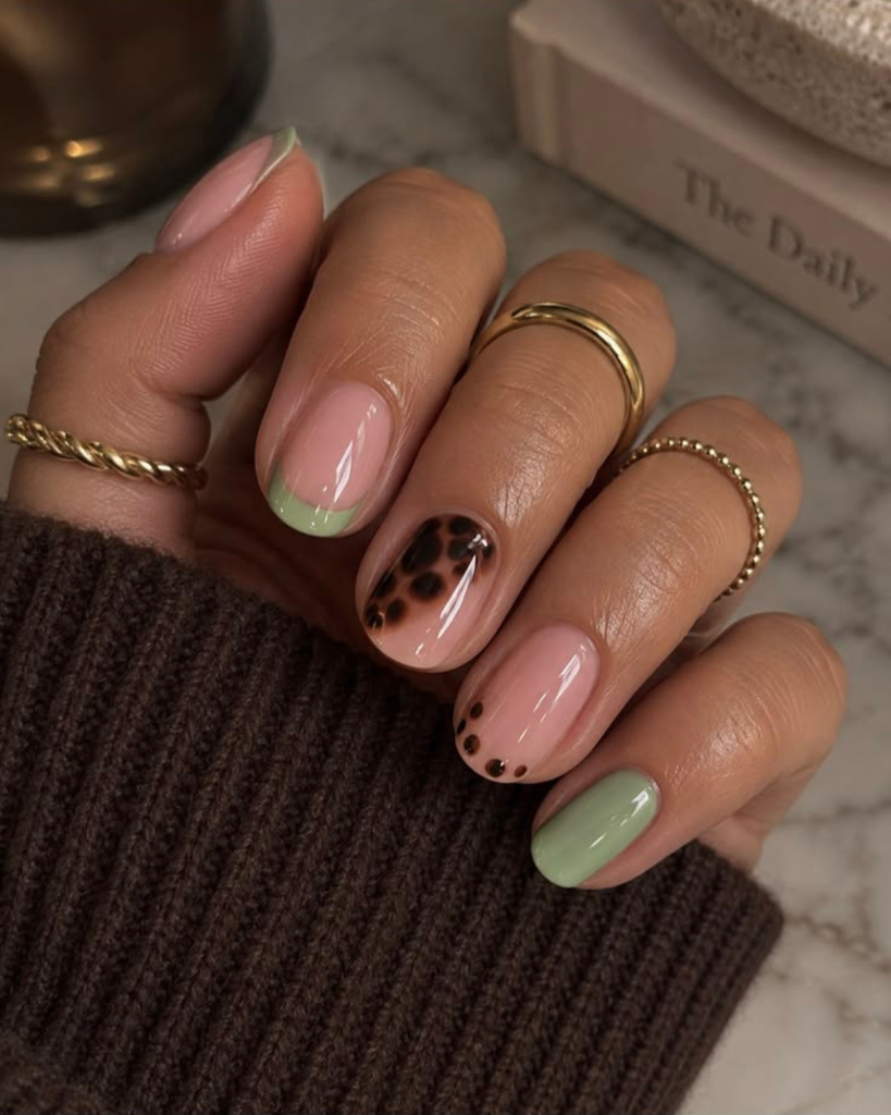 Short nude French tip nails with sage green tips, a tortoiseshell accent and a mint pinky. Short nail designs