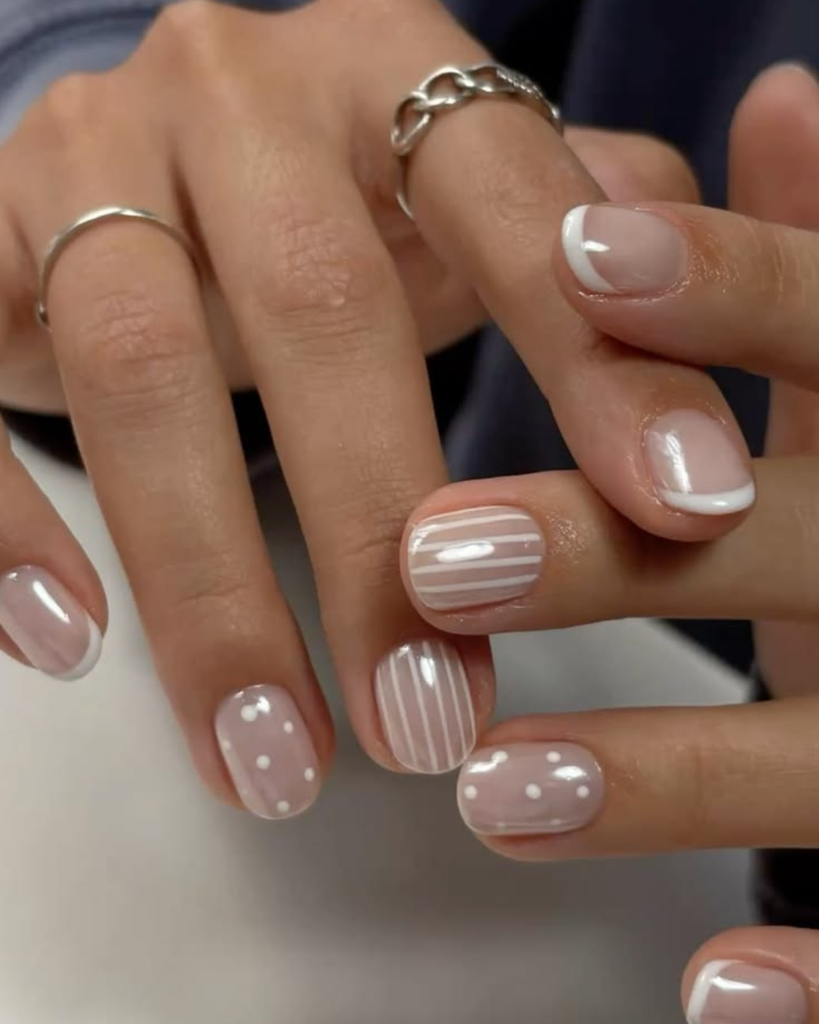 Short sheer nude nails with white and pearl French tips, stripes and polka dots. Short nail designs