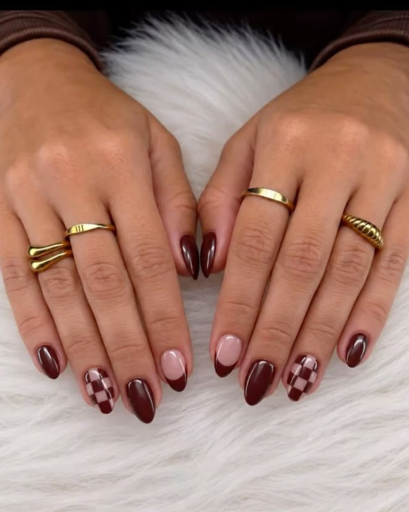 Almond shaped gel nails featuring solid dark brown and burgundy polish, brown and nude checkered accent design, and brown French tips. Short nail design